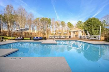 A large swimming pool with a deck and sun loungers.